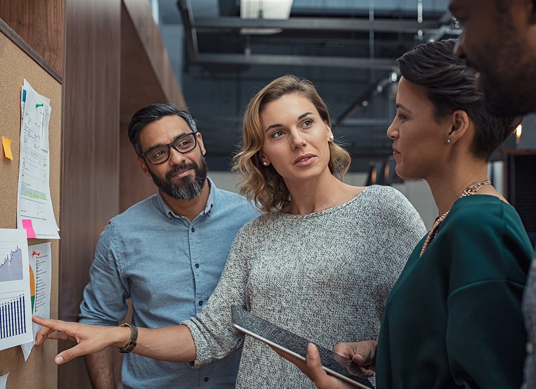 About Our Agency - Group of Professionals Reviewing Information on a Bulletin Board During a Meeting at an Office